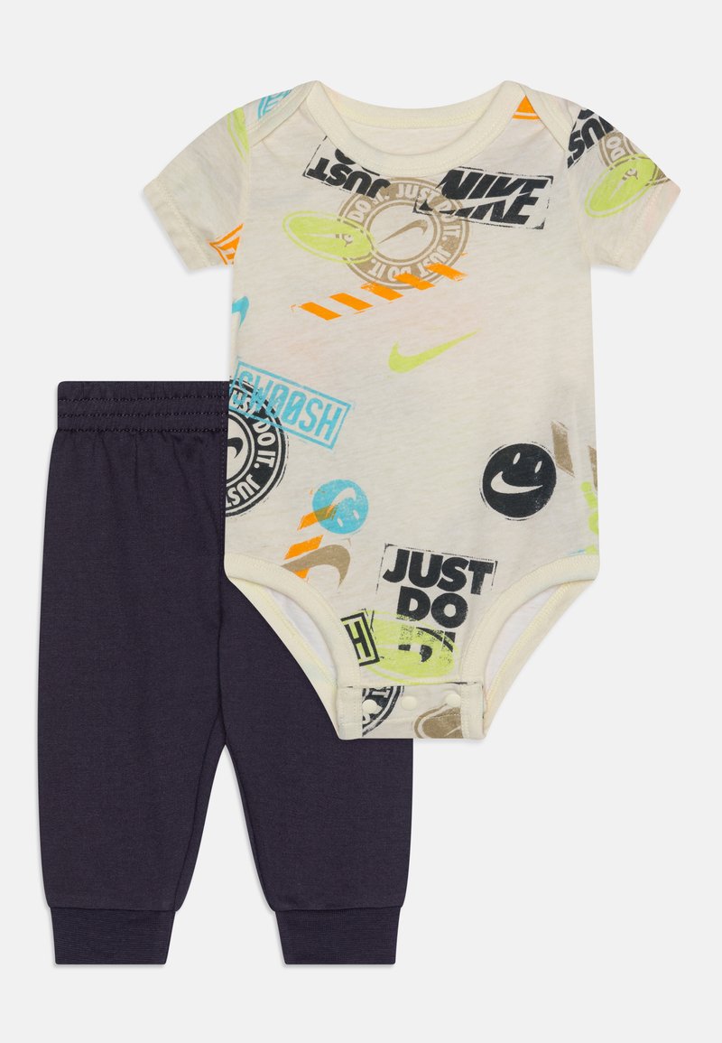 Body krótki rękaw z kolorowymi grafikami inspirowanymi marką Nike, w połączeniu z ciemnoniebieskimi spodniami elastycznymi z pasem w talii dla wygodnego dopasowania.