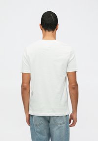 Λευκό βαμβακ�ερό μπλουζάκι με κοντά μανίκια και στρογγυλή λαιμόκοψη. Λείο υλικό, άνετη εφαρμογή και ελάχιστες ραφές στο πίσω μέρος.