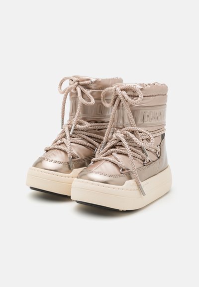 Metallisk beige ankelboots med vadderad ovandel, rund tå och tjock krämfärgad sula. Utrustad med mönstrade snören och förstärkta hällor.