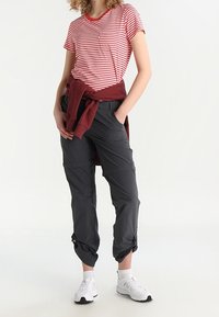 Röd och vit randig t-shirt med kort ärm och rund halsringning, kombinerad med mörkgrå cargobyxor med justerbara cuffs, bärs med vita sneakers.