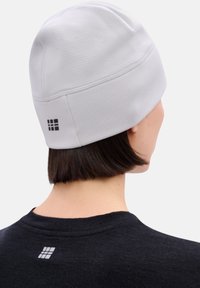 Grijze gebreide muts met gestructureerde stof, aangesloten ontwerp en naaddetails. Logo in zwart aan de achterkant.