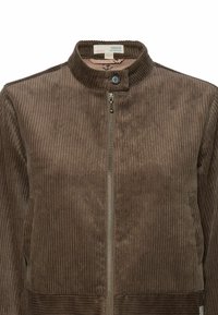 Barna kordbársony dzseki magas gallérral, elöl cipzárral és oldalzsebekkel. A texturált bordás anyag finom mintázatot hoz létre.