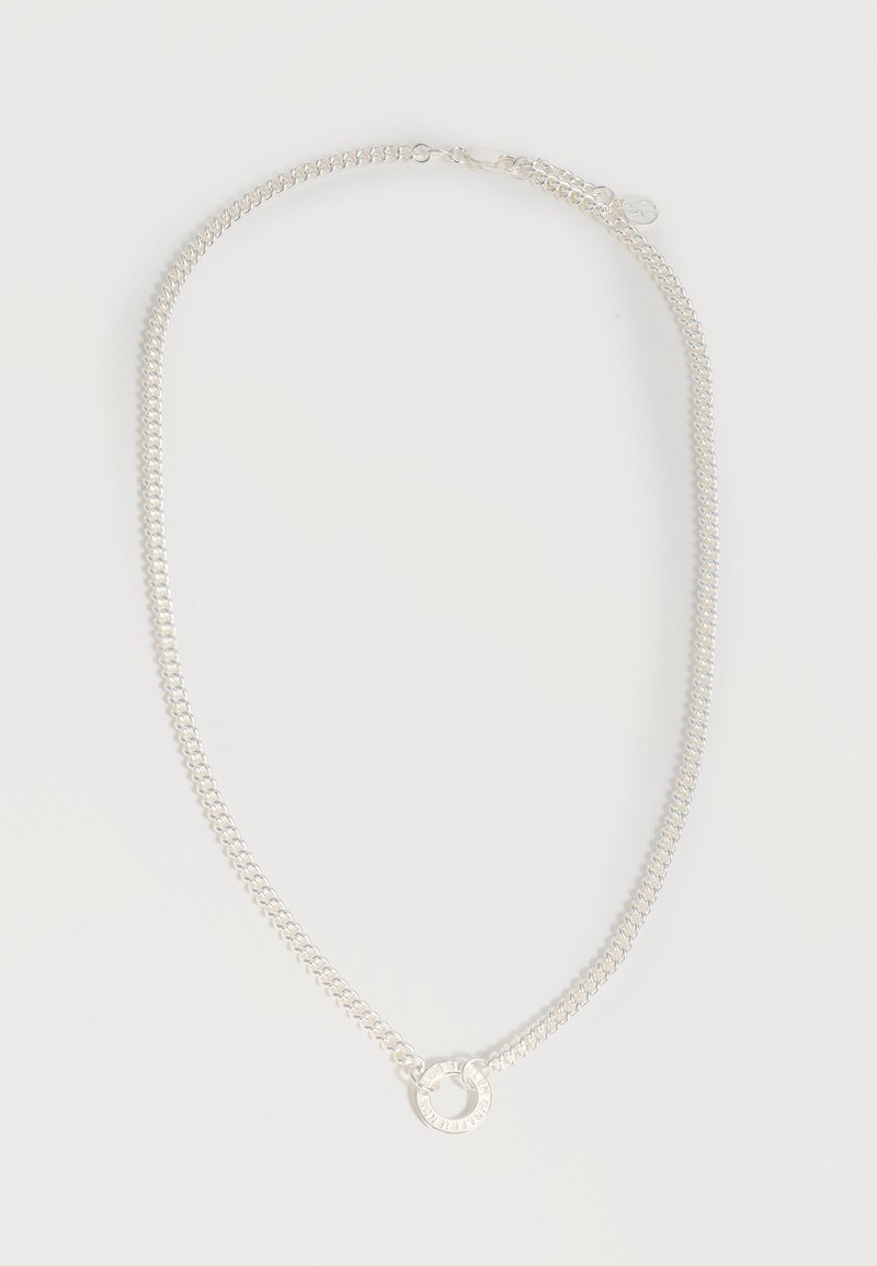 Ασημένιο κολιέ με αλυσίδα και κυκλικό μενταγιόν με χαραγμένο κείμενο, τοποθετημένο επίπεδα σε λευκό φόντο.