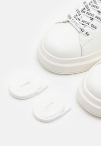 Vita lädersneakers med rund tå, tjock sula och mönstrade skosnören. Inkluderar två set vita skosnören.