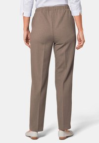 Beige elastische taillebroeken met een rechte pasvorm, voorzien van verticale ribbels en een gladde textuur, gecombineerd met lichtgekleurde schoenen.