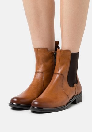 Brązowe skórzane botki za kostkę z elastycznymi panelami po bokach, gładką fakturą, zaokrąglonym noskiem i niskim czarnym obcasem. Zamek błyskawiczny po boku.
