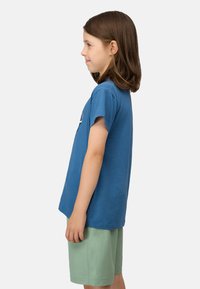 Blauwe katoenen T-shirt met korte mouwen, voorzien van een ronde halslijn en een logo-detail; gecombineerd met lichtgroene shorts.