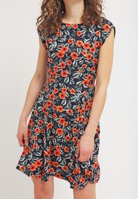Květinové šaty z námořnické tkaniny mají vzor červených a oranžových máků, volány na ramenou a rozšířenou sukni. Jemný, lehký materiál.