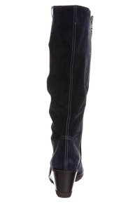 Bota de ante azul marino hasta la rodilla con tacón en cuña, con costuras blancas contrastantes y un cierre lateral para facilitar su uso.