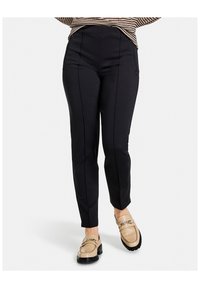 Svarta figurna byxor med framseam, hög midja och två sidfickor, tillsammans med beige loafers med kedjedetalj.