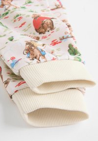 Puuvillapajama-housut vaaleanpunaisella taustalla ja värikkäillä sarjakuvamaisten eläinten kuvioilla. Raitaiset vaaleanbeiget hihnat. Pehmeä tekstuuri.