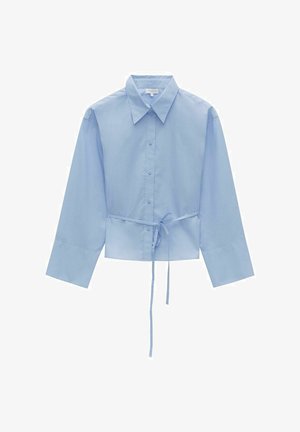 Ljusblå beskuren skjorta i mjuk bomull, med klassisk krage, långa ärmar, knäppning framtill och ett bälte i midjan.