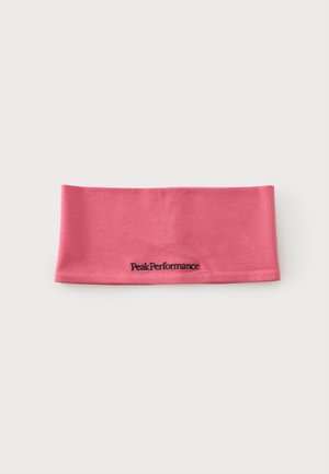 Pink stofhovedbånd med "Peak Performance" broderet i sort centreret på en ensfarvet lys baggrund.