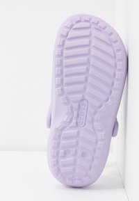 Suola di una scarpa Crocs di colore viola chiaro che mostra un motivo di battistrada testurizzato con il logo Crocs e le indicazioni della taglia.