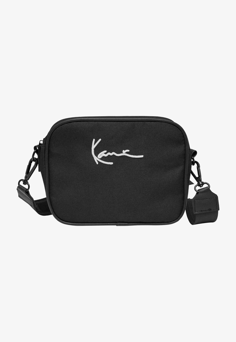 Borsa a tracolla in tessuto nero con chiusura a zip. Nota firma ricamata in bianco sulla parte anteriore. Cintura regolabile con hardware a clip.