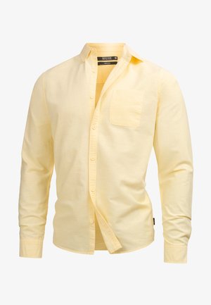 Žltá košeľa s dlhým rukávom, tlačená z bavlny, s golierom, náprsníkovou vreckom a voľným strihom. Hladká textúra s jemným švom.