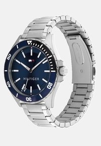 Reloj de acero inoxidable plateado con una esfera azul, marcadores de hora blancos en negrita, ventana de fecha y bisel giratorio con números blancos y un logotipo de acento.