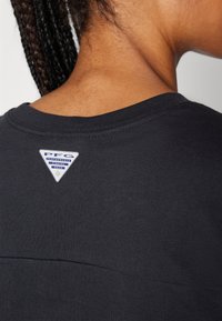 Black t-shirt featuring a crew neck and short sleeves, with a blue and white PFG logo tag stitched at the back neck area.