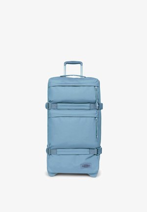 Pequeña maleta blanda azul con asa telescópica, bolsillos frontales con cremallera, correas laterales y logotipo de Eastpak sobre fondo blanco.
