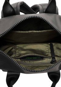 Mochila negra con cierre de cremallera. El interior cuenta con un forro de color verde oliva, dos compartimentos y un pequeño bolsillo con cremallera.