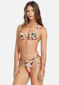 Bikini-set med svart botten och flerfärgad blommönster, rynkig topp och justerbara snörning vid sidorna, tillverkad av mjukt material.