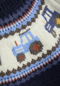 Tessuto lavorato a maglia con un trattore blu e motivi di gomme nei colori marrone, arancione, crema e blu su uno sfondo blu scuro.