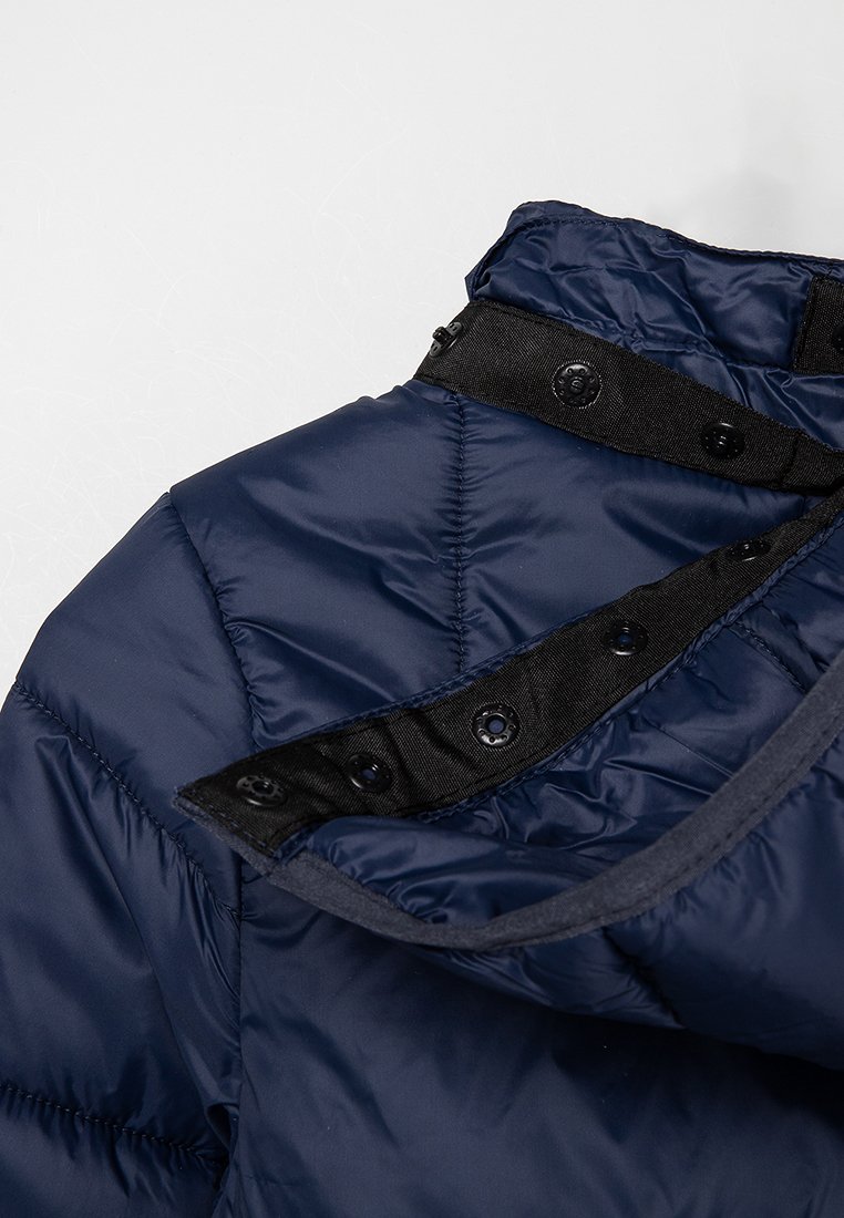Giubbotto puffer blu navy con un motivo trapuntato, dotato di una chiusura a scatto nera al colletto e di una morbida fodera interna.