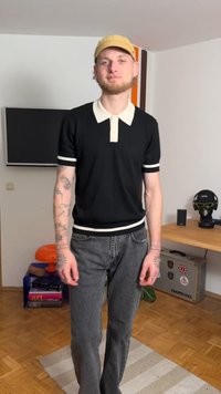 Μαύρο πόλο μπλουζάκι με λευκό γιακά και μανσέτες, συνδυασμένο με ξεβαμμένο γκρι τζιν. Αξεσουάρ περιλαμβάνουν ένα ανοιχτόχρωμο καπέλο. Μινιμαλιστικός σχεδιασμός.