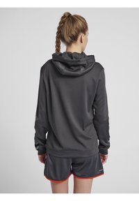 Felpa con cappuccio grigio scuro con un motivo testurizzato, polsini a coste e cappuccio con cordino, abbinata a pantaloni corti neri con accenti rossi.