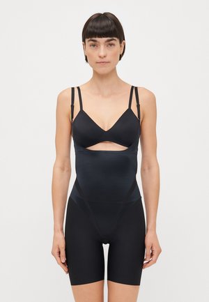 Shapewear noir avec design découpé, présentant une texture lisse, des bretelles réglables et une longueur mi-cuisse. Fabriqué en tissu extensible et léger.