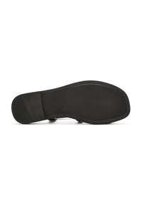 Suola di scarpa nera in gomma, caratterizzata da una superficie testurizzata, forma arrotondata e dettagli di design sottili. Gli angoli sono lisci e si notano poche etichette di branding.