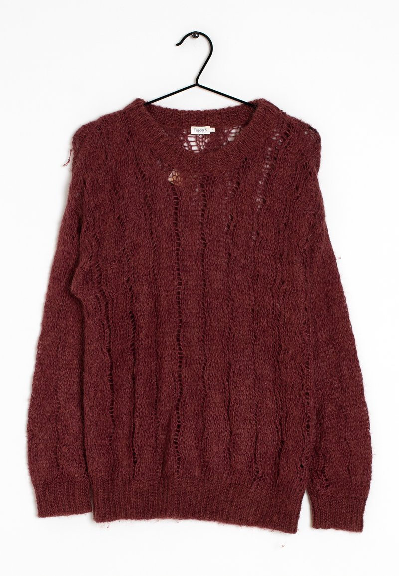 Pull en tricot marron avec motifs torsadés suspendu à un cintre noir sur un fond blanc.