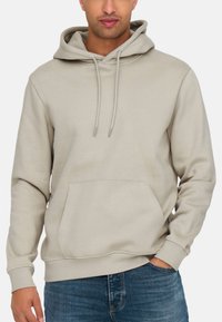 Lys beige hoodie med en frontlomme, snoretræk og ribbede ærmer og kant. Fremstillet af blødt, tekstureret materiale, designet til komfort.