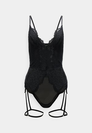 Body en dentelle noire avec fines bretelles, motifs floraux en dentelle, et jarretelles attachées sur un fond blanc uni.