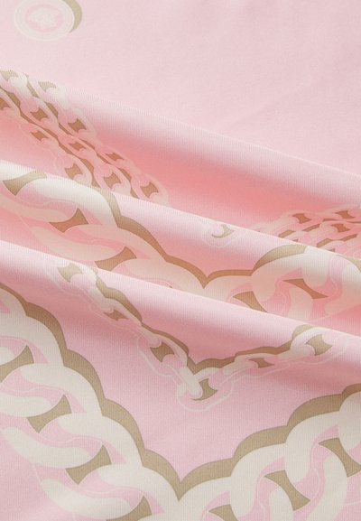 Silky fabric in light pink with a wavy chain pattern in white and gold. Texture is smooth, with a subtle sheen and intricate detailing.