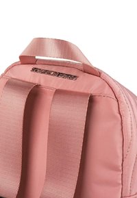 Mochila rosa con un exterior suave y satinado, correas acolchadas y un logotipo brillante de "Skechers". Cuenta con dos asas en la parte superior.