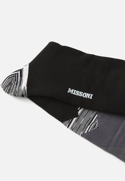 Sorte og grå sokker med et mønsterdesign. Merkenavnet "MISSONI" er brodert i hvitt på mansjetten. Mykt materiale.