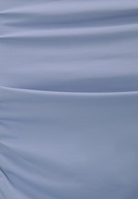 Světle modrá tkanina se hladkou strukturou, s jemnými záhyby a decentním leskem, navržená pro estetiku drapérie.