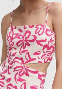 Biała krótka bluzka z różowym wzorem w kwiaty, z cienkimi ramiączkami i wycięciem z boku. Wykonana z lekkiego materiału.