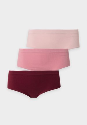 Woman standing barefoot wearing a light blue bra and maroon high-waisted underwear against a plain light background.