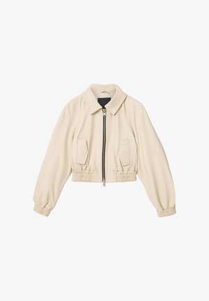 Kremfarvet kort jakke med lynlås foran, to klaplommer, elastisk talje og elastiske manchetter.