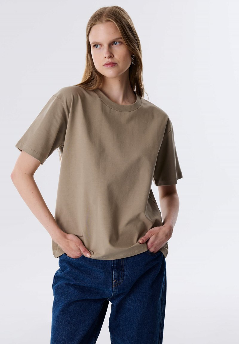 Beige katoenen t-shirt met een relaxed fit, ronde halslijn, korte mouwen en subtiele textuur, gecombineerd met blauwe denim.