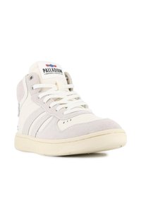Basket haute beige et crème avec lacets blancs, accents en suède et logo Palladium sur la languette, présenté sous un angle bas et frontal.
