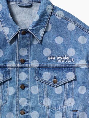 Veste en jean bleu clair avec de gros pois blancs, des boutons marron, des poches avant et "gap·awake new york" brodé sur la poitrine.