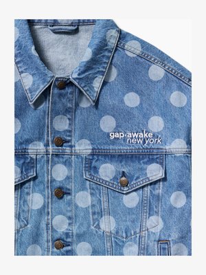 Veste en jean bleu clair avec de gros pois blancs, des boutons marron, des poches avant et "gap·awake new york" brodé sur la poitrine.