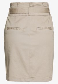 Jupe crayon beige en coton avec une texture lisse, dotée d'une taille haute, de deux poches arrière et d'un accent en bouton à la taille.