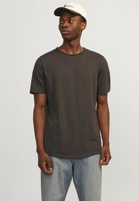 Dunkelgraues T-Shirt mit kurzen Ärmeln und Rundhalsausschnitt, aus weichem Material, kombiniert mit hellblauen Jeans und einer cremefarbenen Baseballmütze.