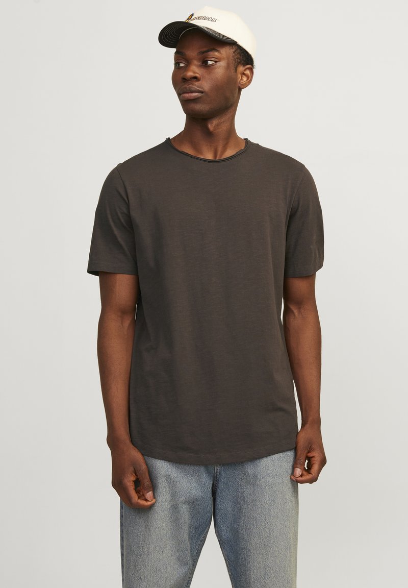 Dunkelgraues T-Shirt mit kurzen Ärmeln und Rundhalsausschnitt, aus weichem Material, kombiniert mit hellblauen Jeans und einer cremefarbenen Baseballmütze.