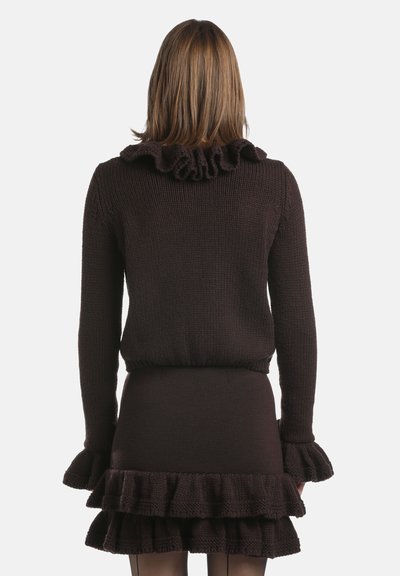 Ruskea neulottu neulepaita, jossa röyhelökaulus ja -hihansuut, vartalonmyötäinen vyötärö sekä kerroksittain röyhelöity helma, näyttää teksturoidun kankaan.