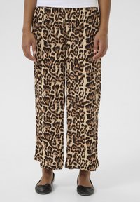 Pantalons à jambe large en tissu beige avec un motif léopard noir et marron. Texture lisse, dotés d'une taille mi-haute et de plis.